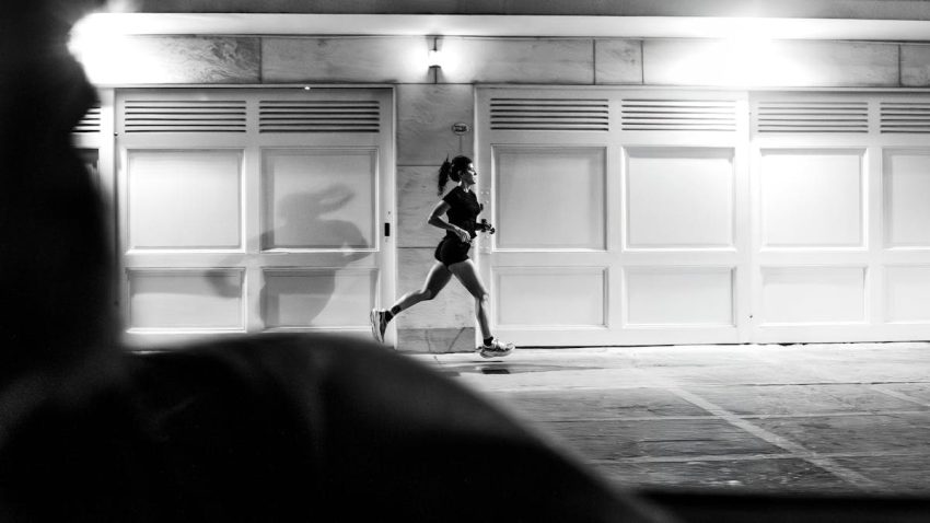 A woman running at night in Buenos Aires, showcasing urban life in black and white.